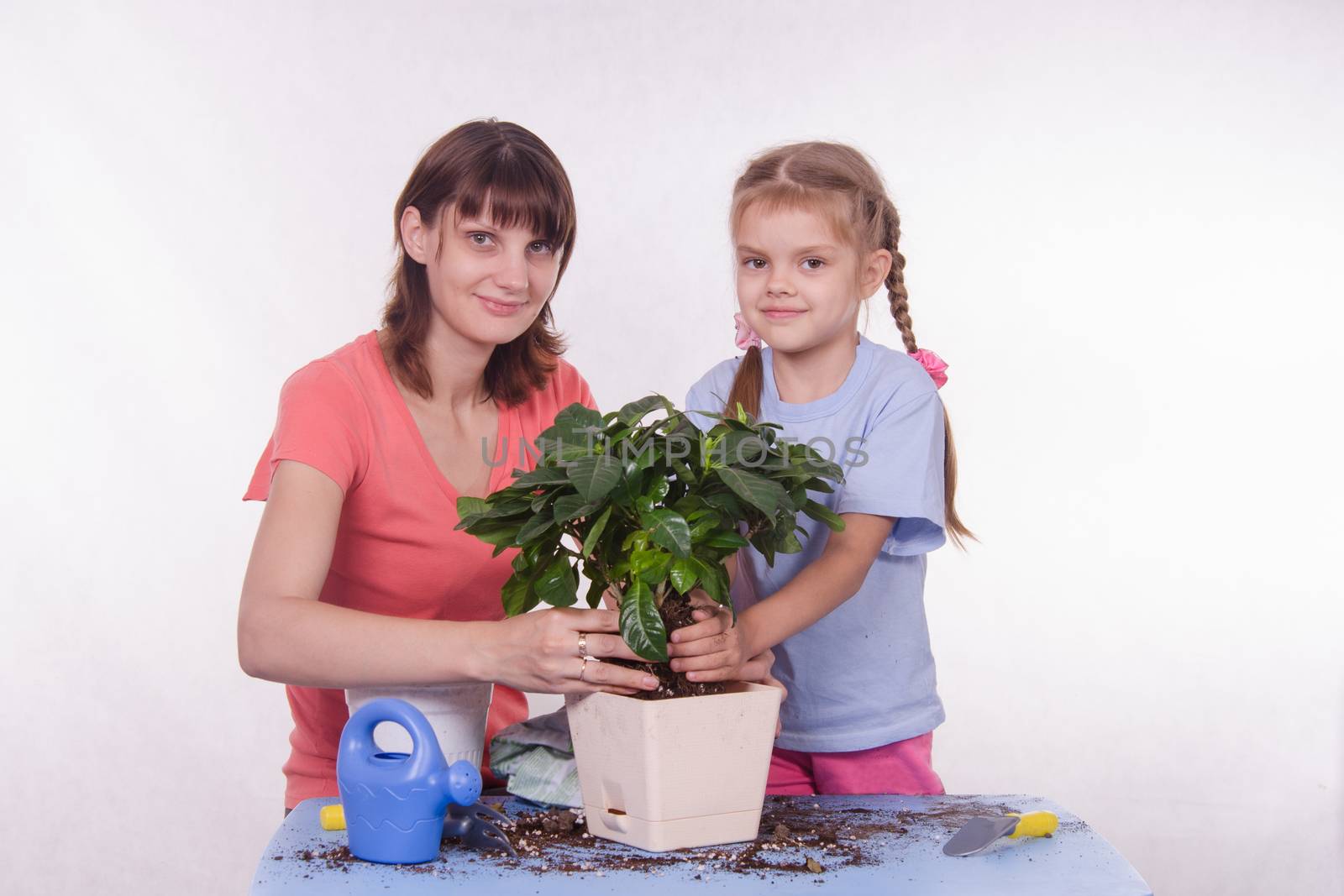 Mom and daughter planting new houseplant in a pot by Madhourse