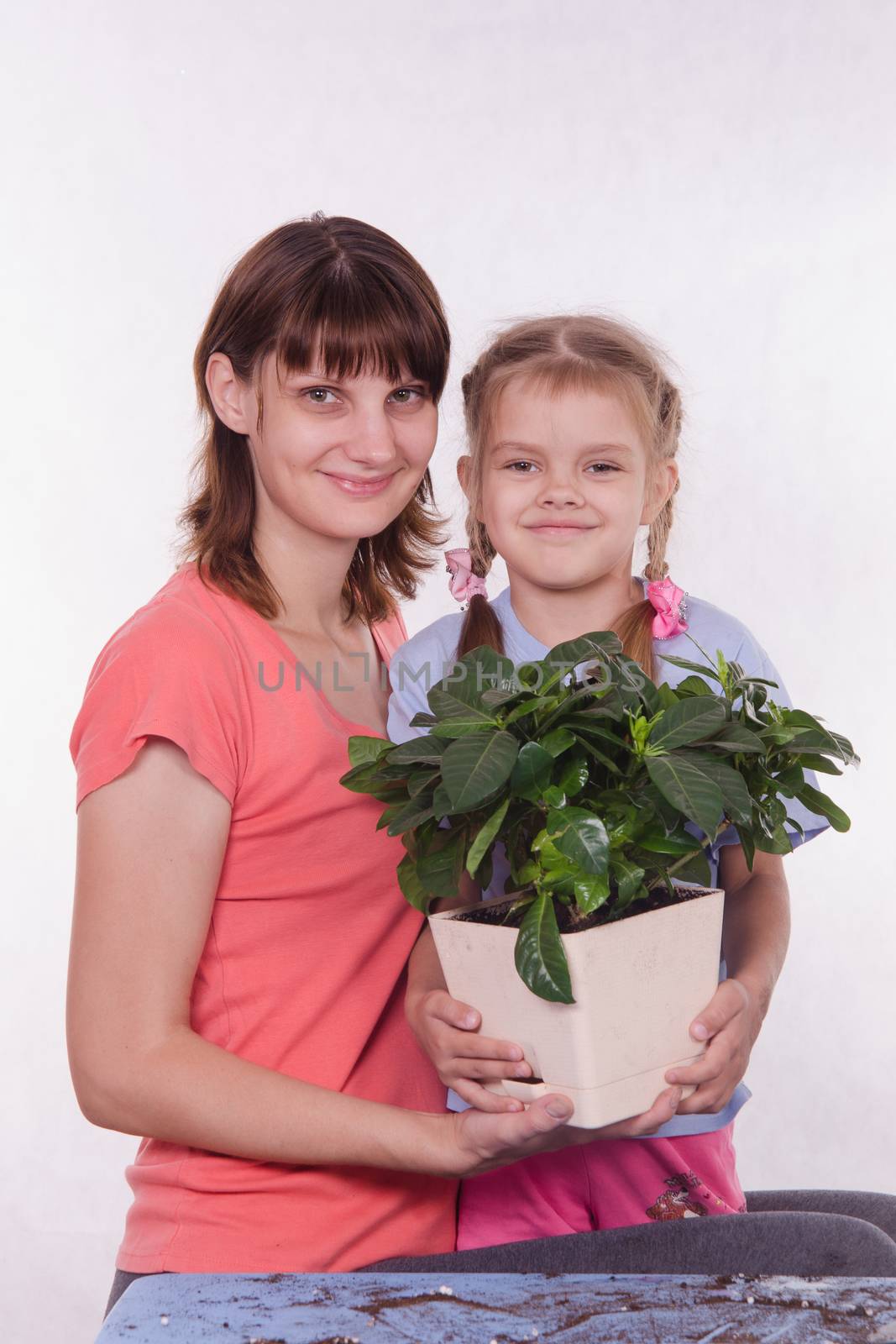 Mom and daughter with a potted flower in hands by Madhourse