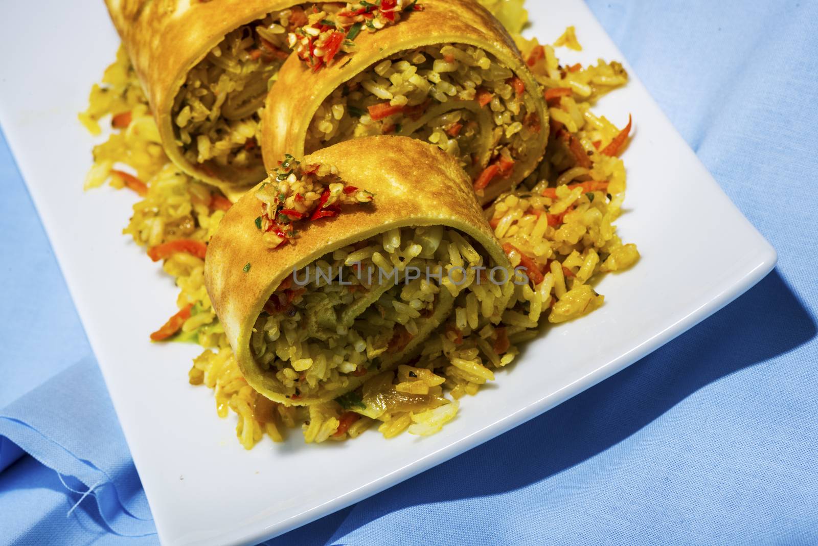 asian curry rice roll cutted as a sushi in a white plate on blue napkin