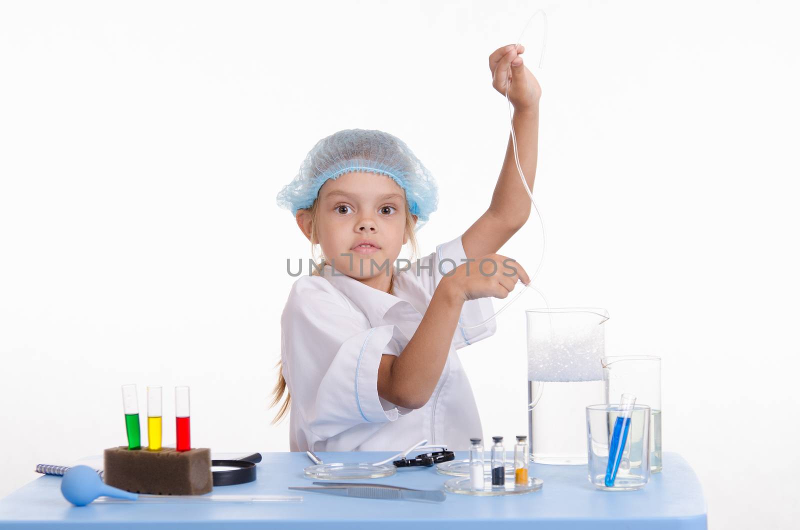 Chemist girl sitting at the table with the reagents in chemistry class and puts experiments