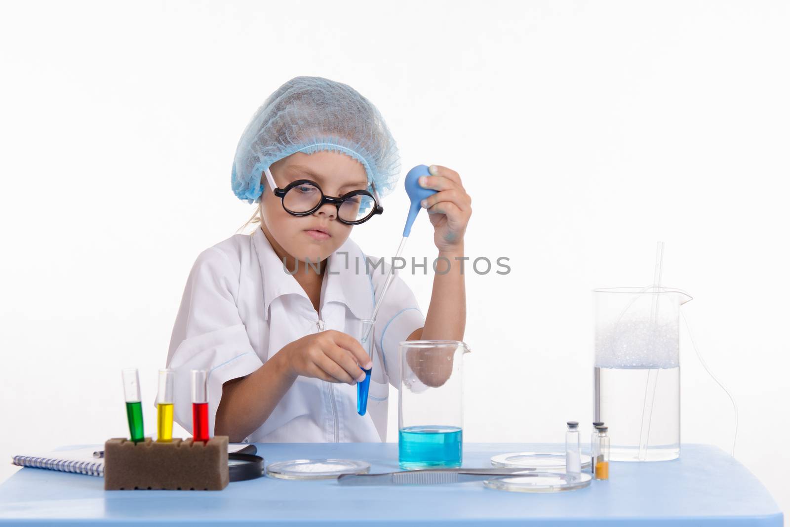 Chemist girl sitting at the table with the reagents in chemistry class and puts experiments