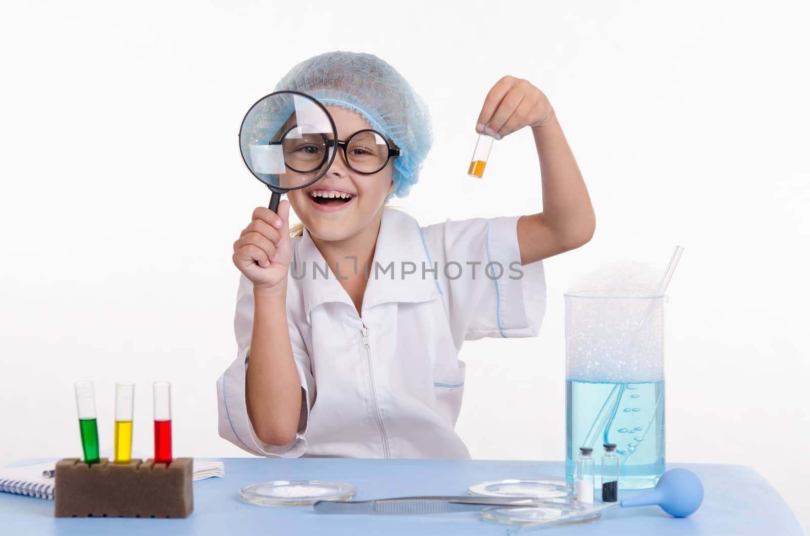 Chemist girl sitting at the table with the reagents in chemistry class and puts experiments