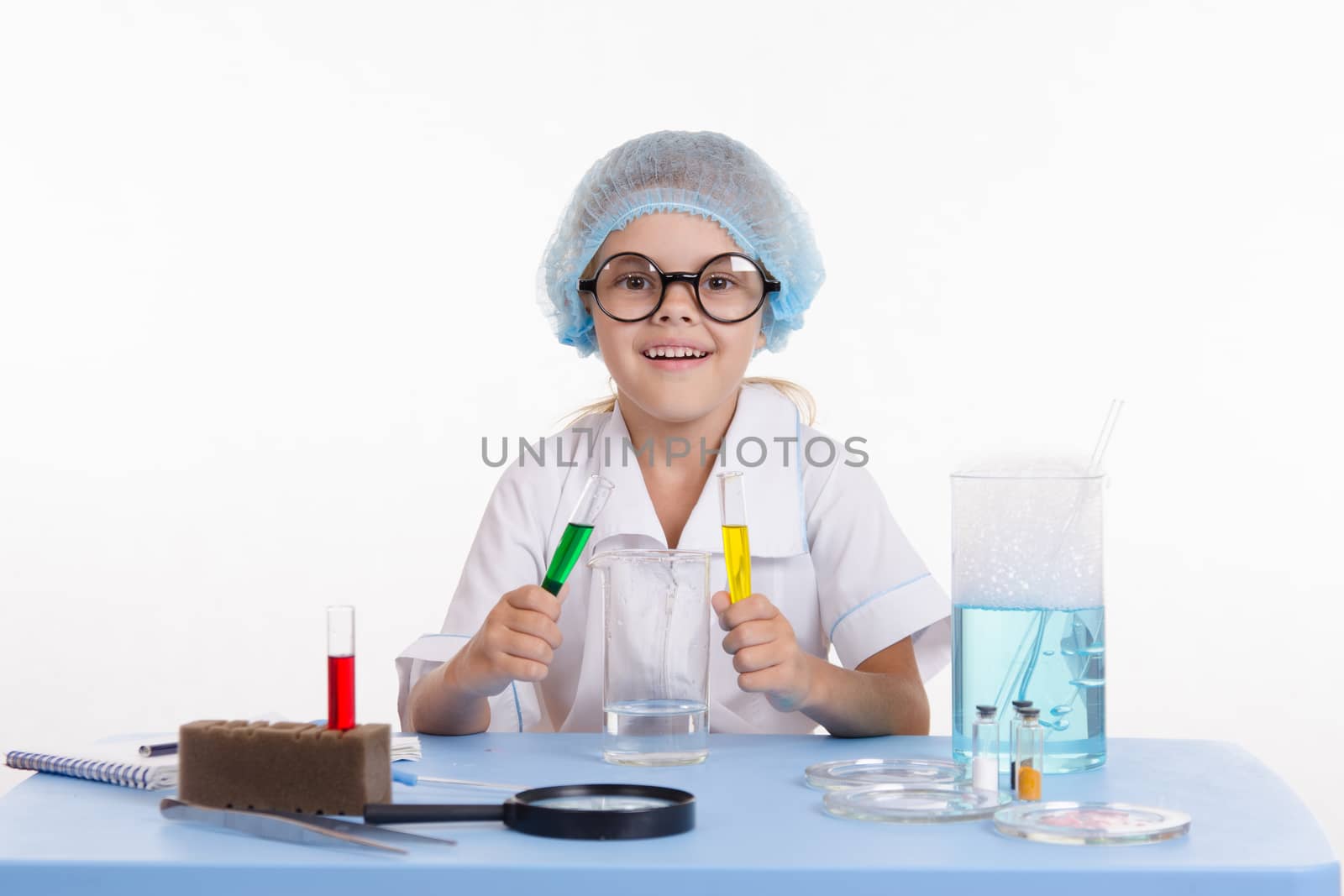 Chemist girl sitting at the table with the reagents in chemistry class and puts experiments