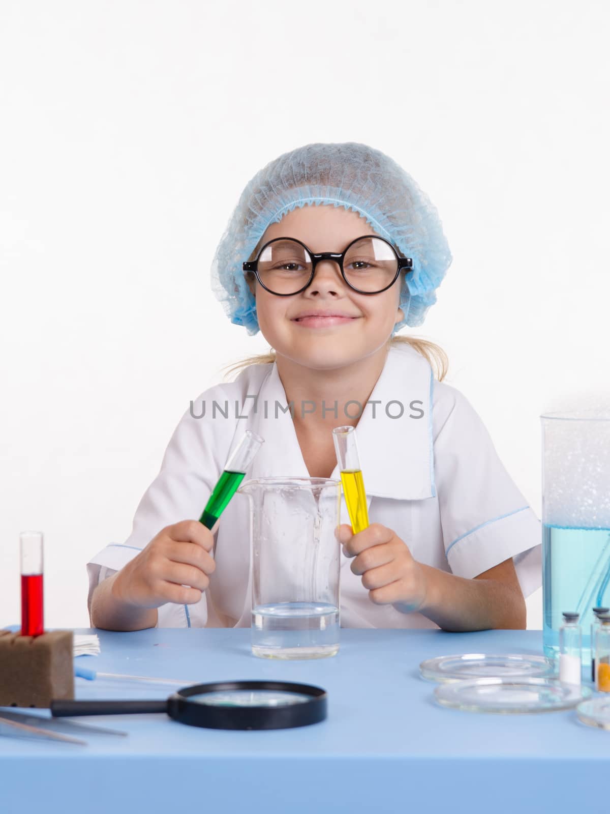 Chemist girl sitting at the table with the reagents in chemistry class and puts experiments