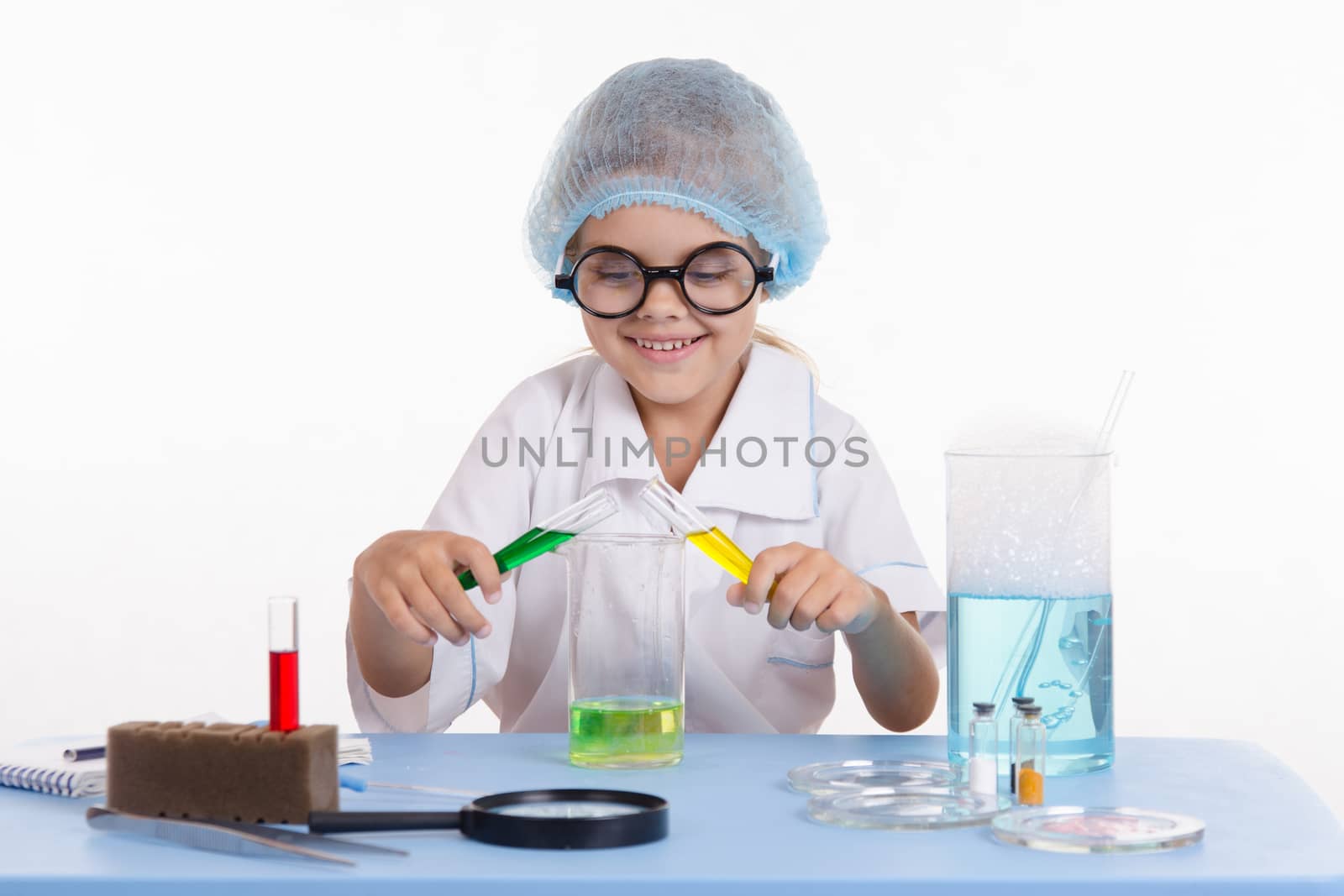 Chemist girl sitting at the table with the reagents in chemistry class and puts experiments