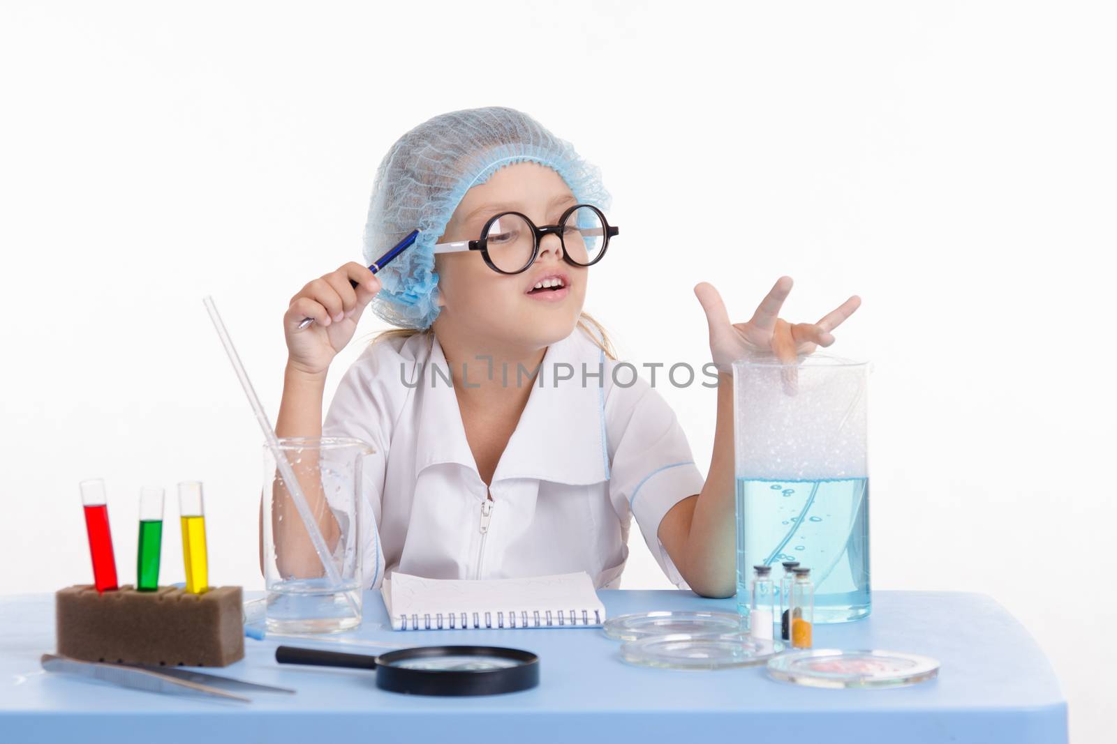 Chemist girl sitting at the table with the reagents in chemistry class and puts experiments