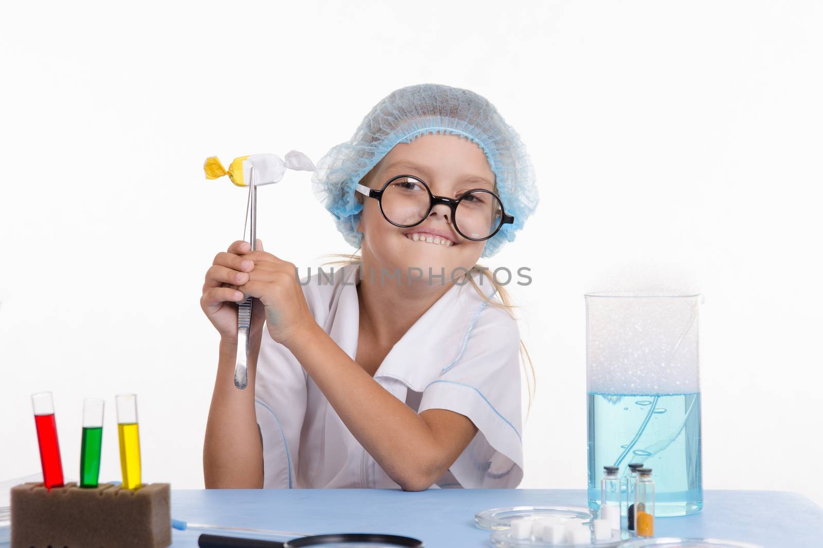 Chemist girl sitting at the table with the reagents in chemistry class and puts experiments
