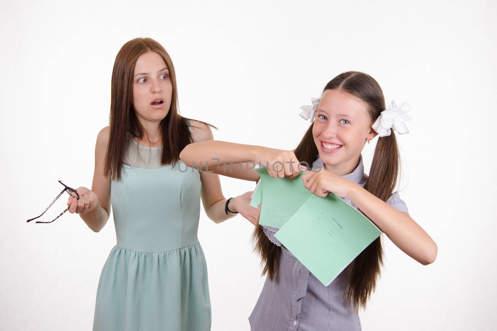 Schoolgirl having fun tearing the notebook in front of an angry teacher