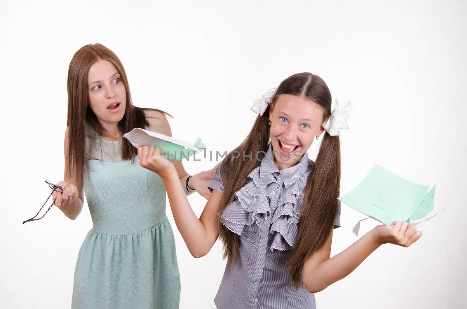 Schoolgirl having fun tearing the notebook in front of an angry teacher