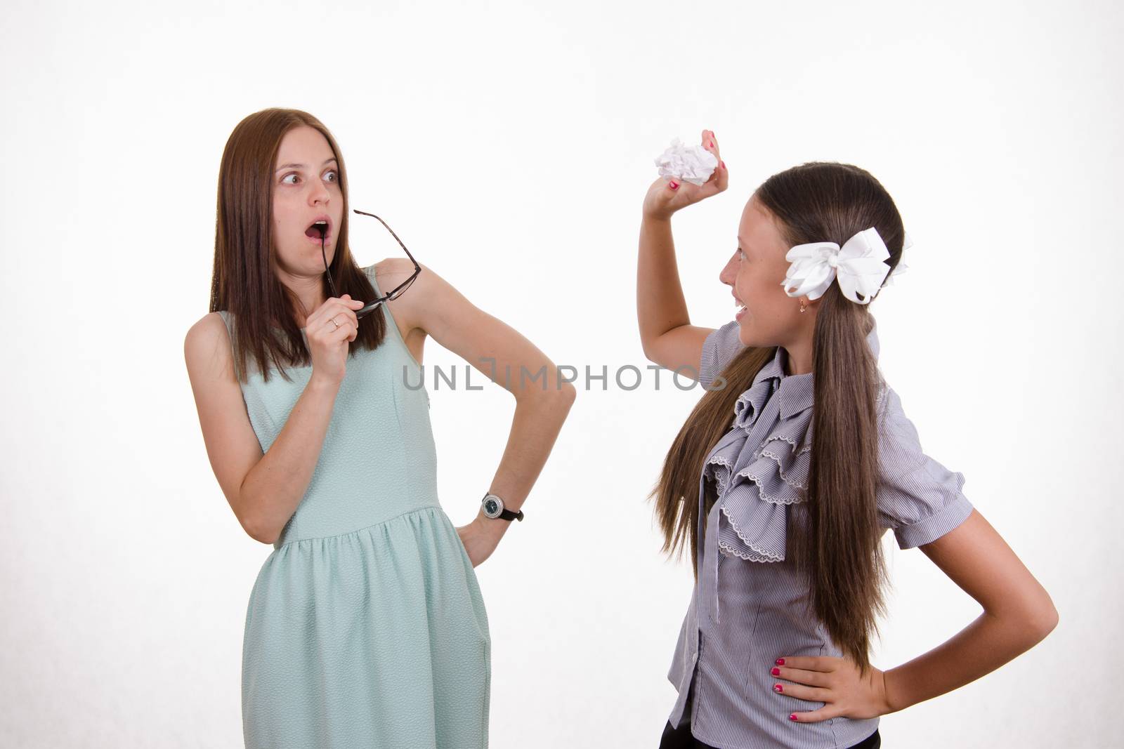 Schoolgirl having fun tearing the notebook in front of an angry teacher