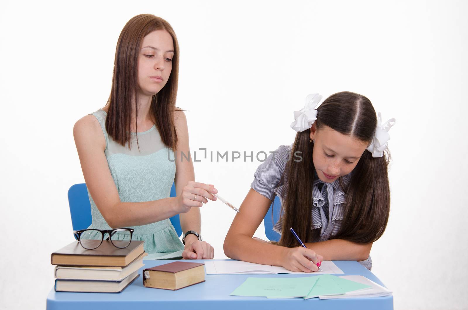 Teacher teaches the student sitting with him at the table
