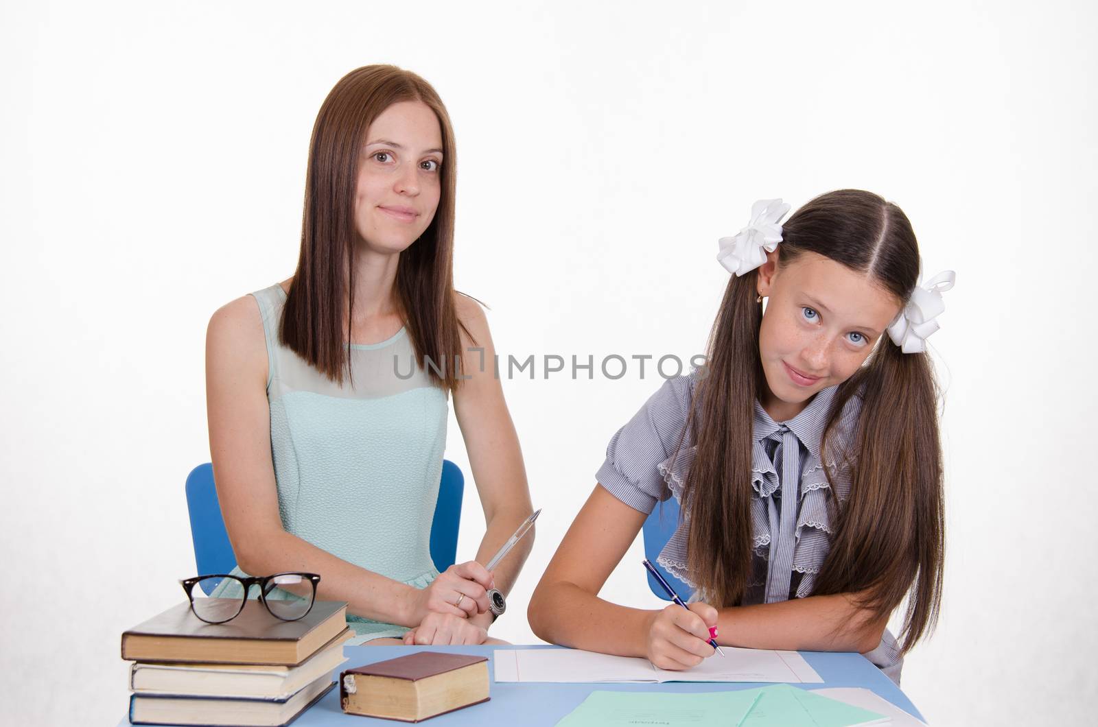 Teacher teaches the student sitting with him at the table