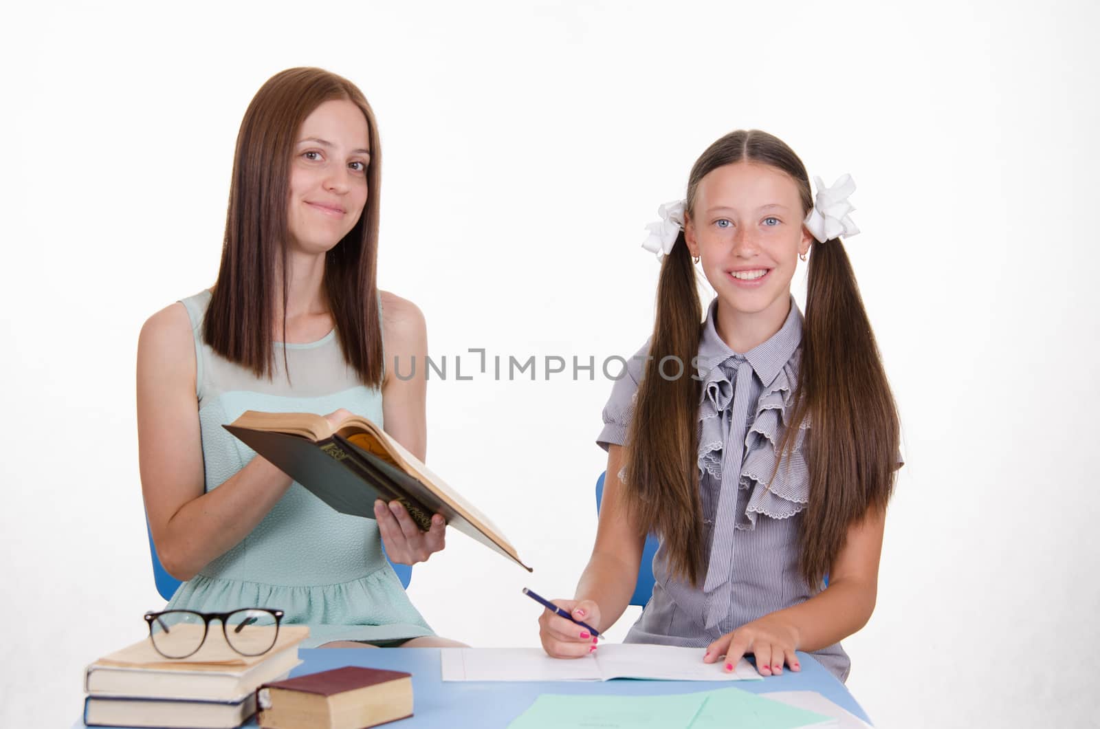 Teacher teaches the student sitting with him at the table