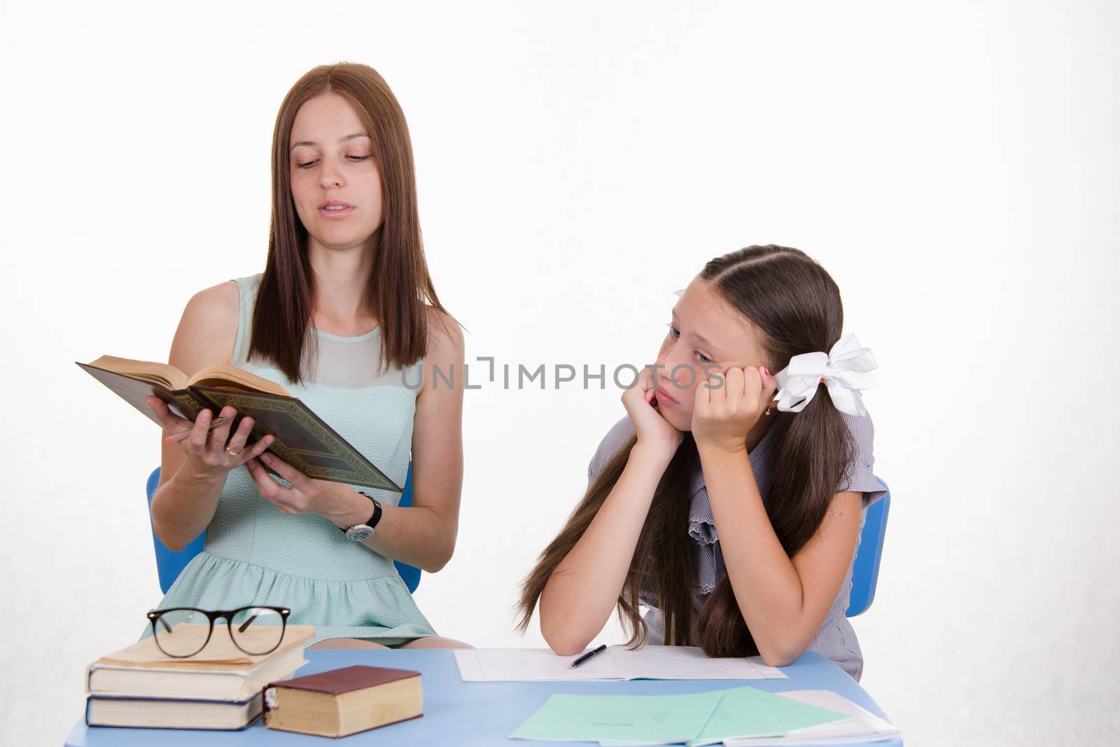 Teacher teaches the student sitting with him at the table