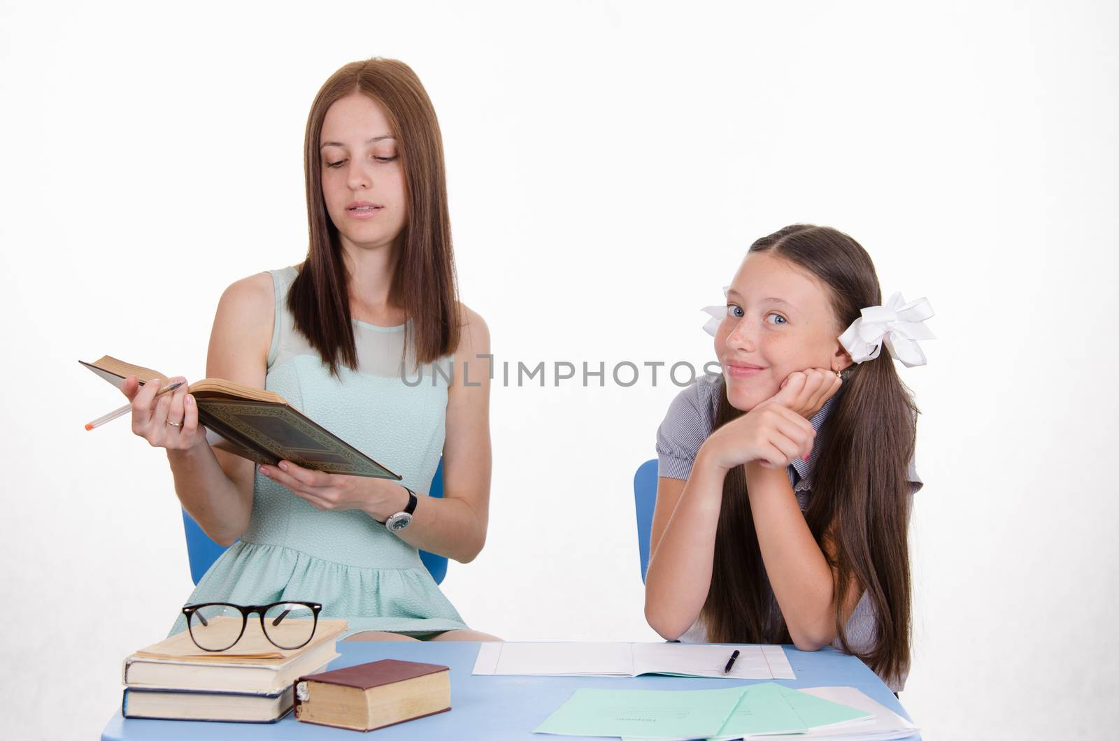 The teacher reads student assignments from textbook by Madhourse