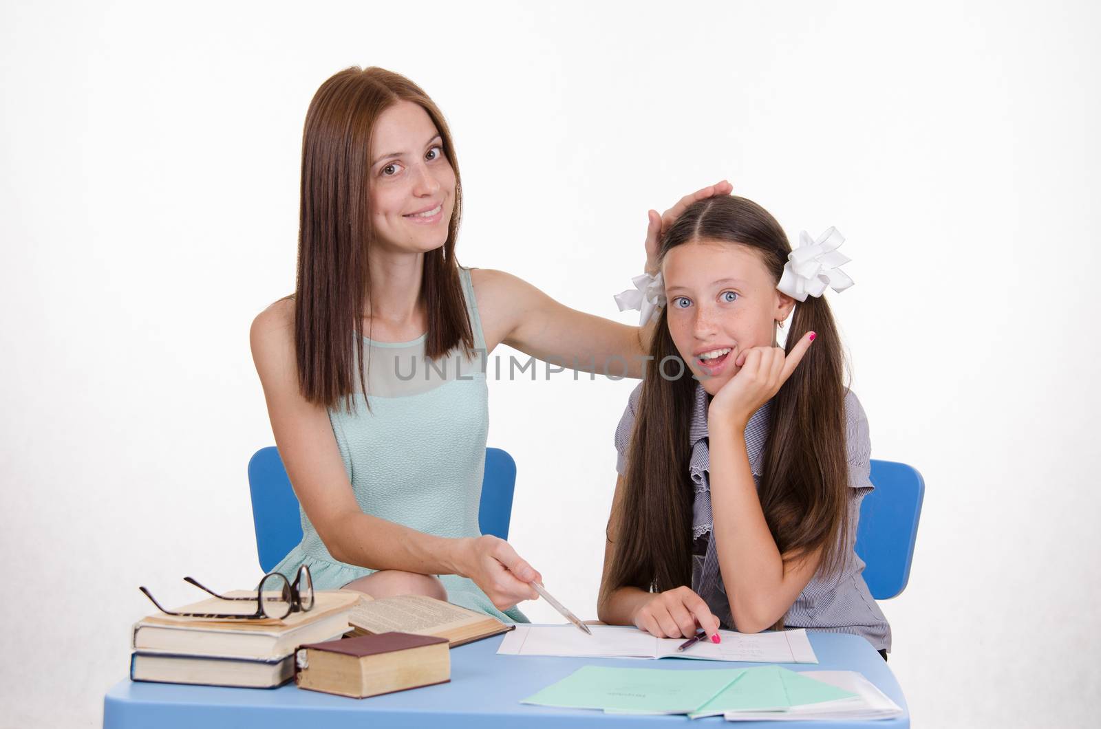 The teacher teaches the student sitting with him at the table