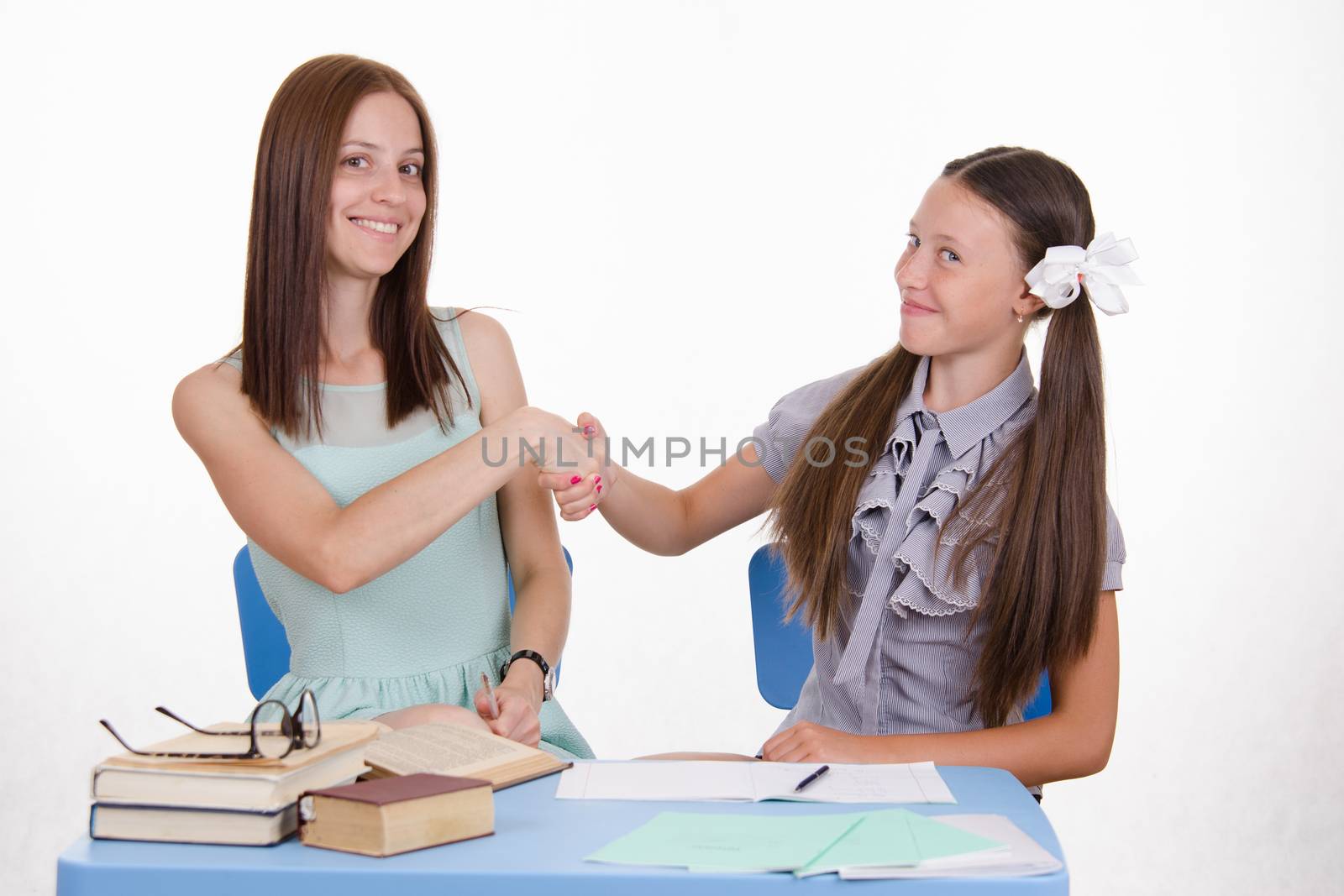The teacher teaches the student sitting with him at the table