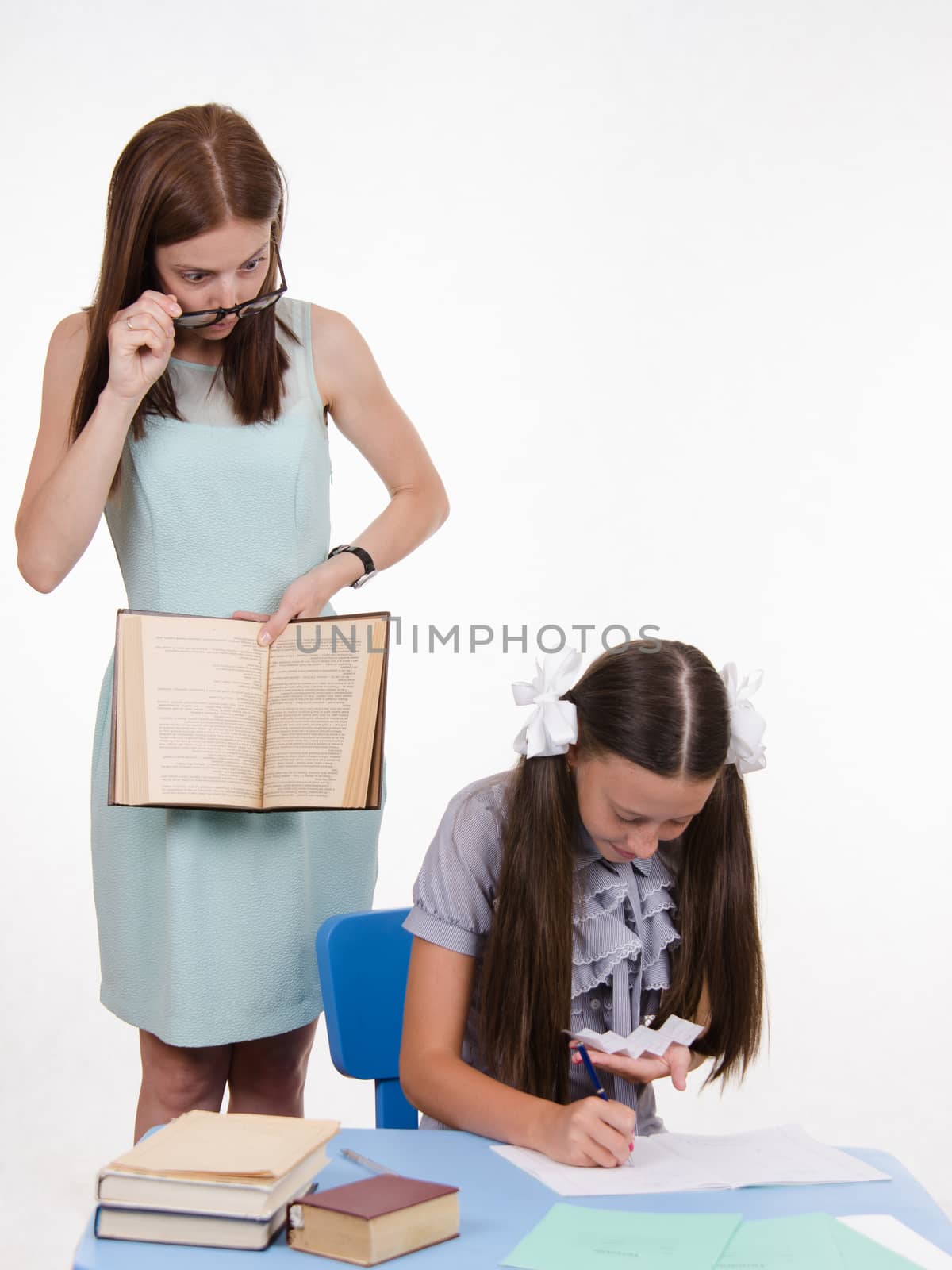 Teacher standing at desk behind which sits a pupil is deducted from the Crib