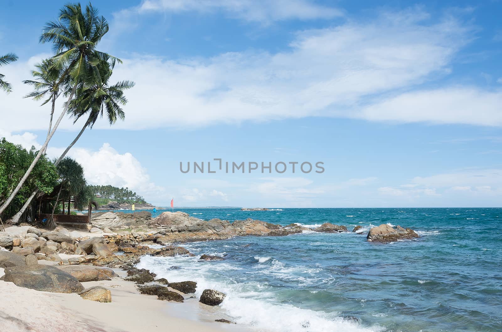 Tropical rocky beach with coconut palm trees, sandy beach and ocean. Tangalle, Southern Province, Sri Lanka, Asia.