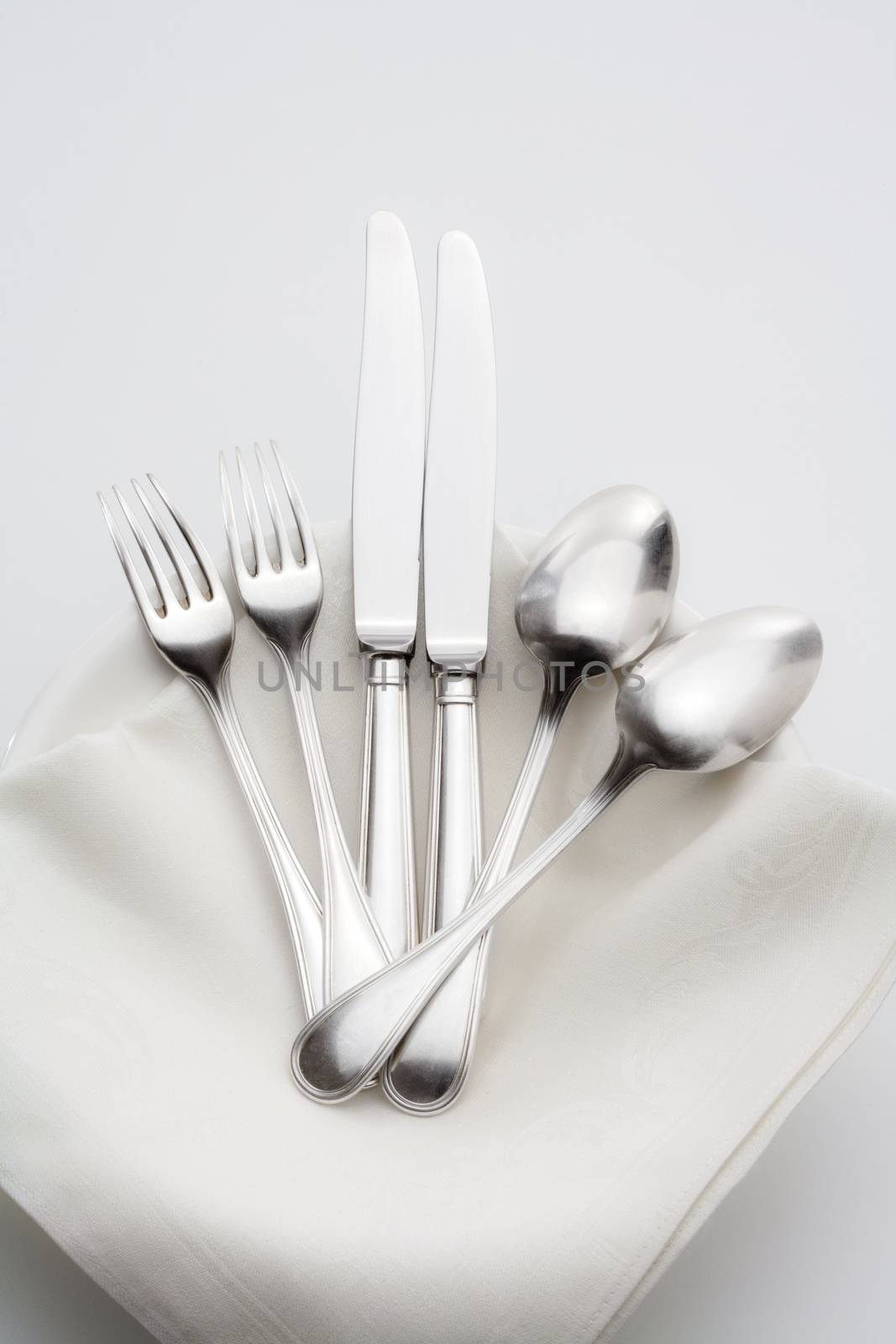 elegant silverware on a pile of plates with white cloth