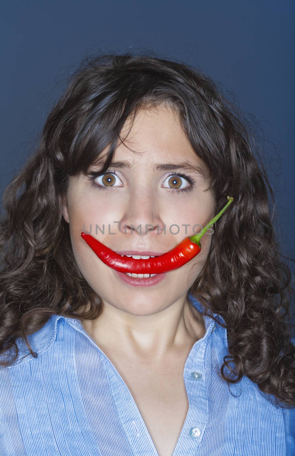 young brunette woman holding chili in her mouth