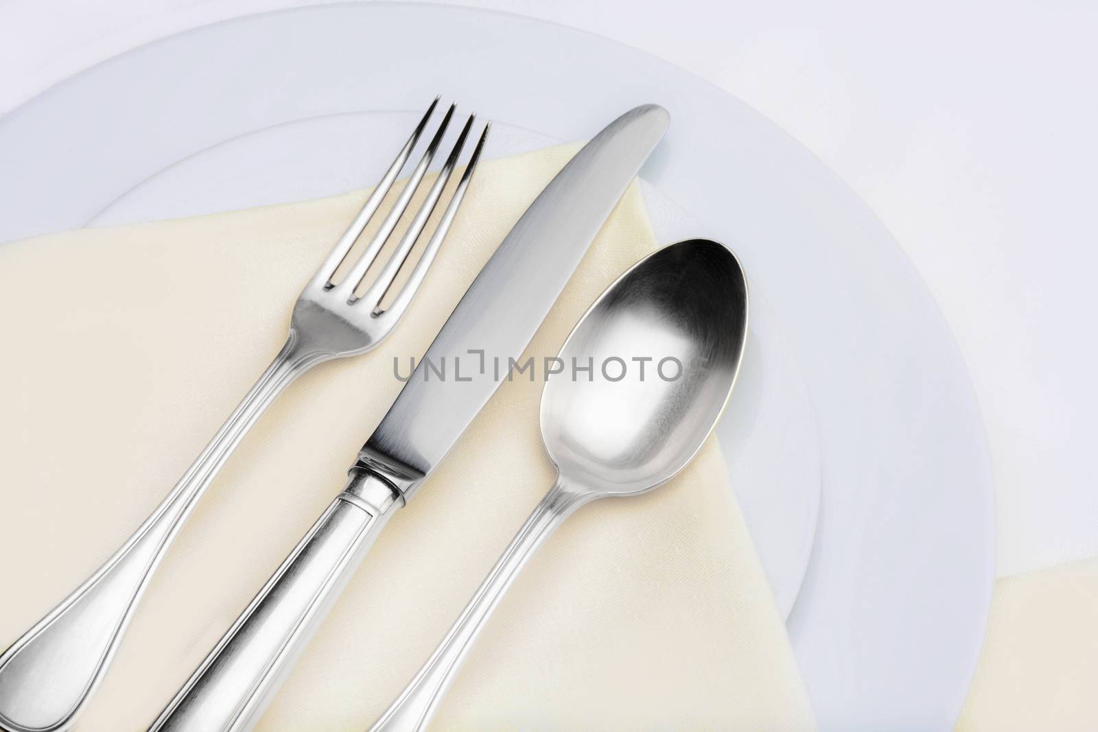 closeup of silverware on plates with yellow cloth
