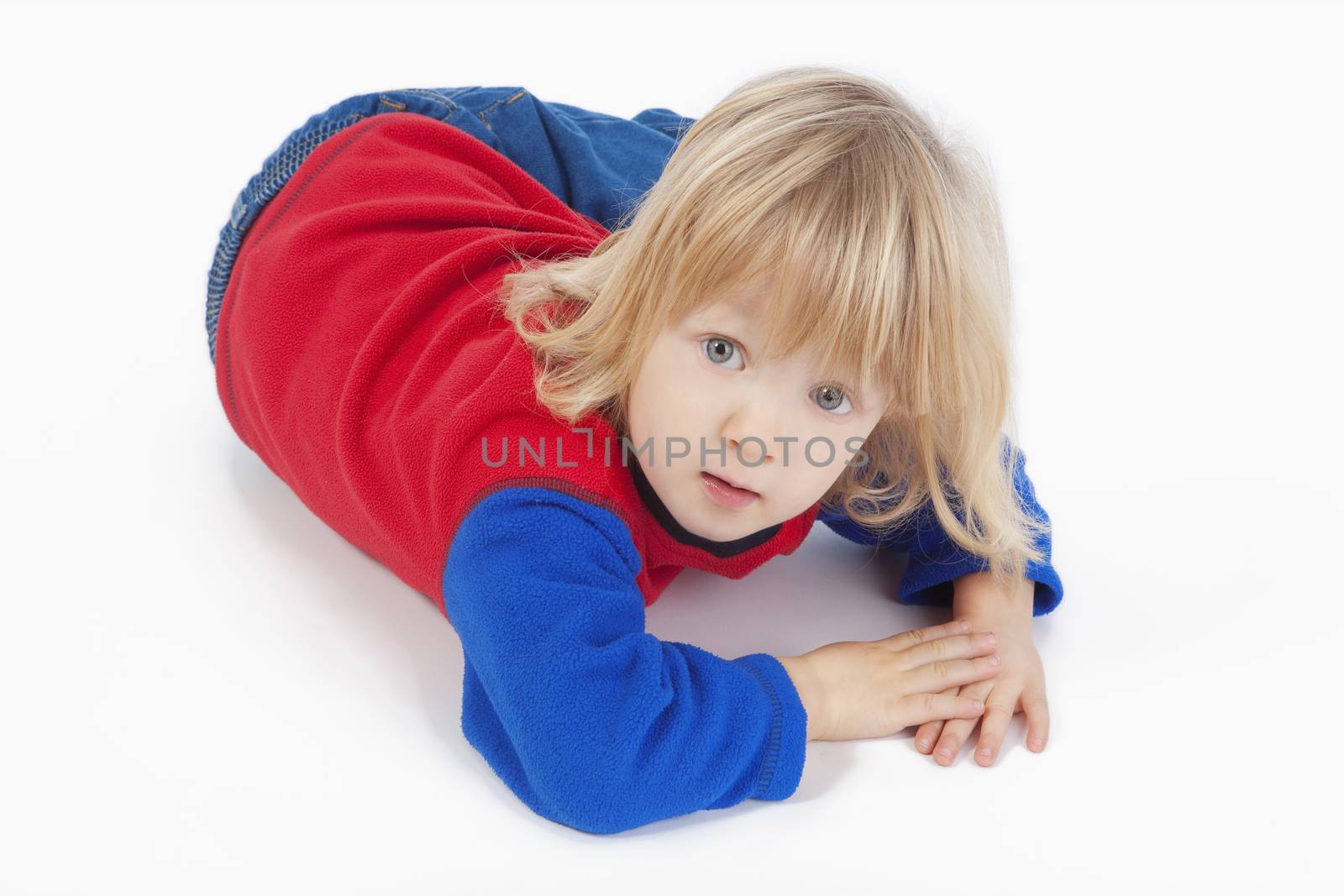 boy with long blond hair lying down, looking at camera