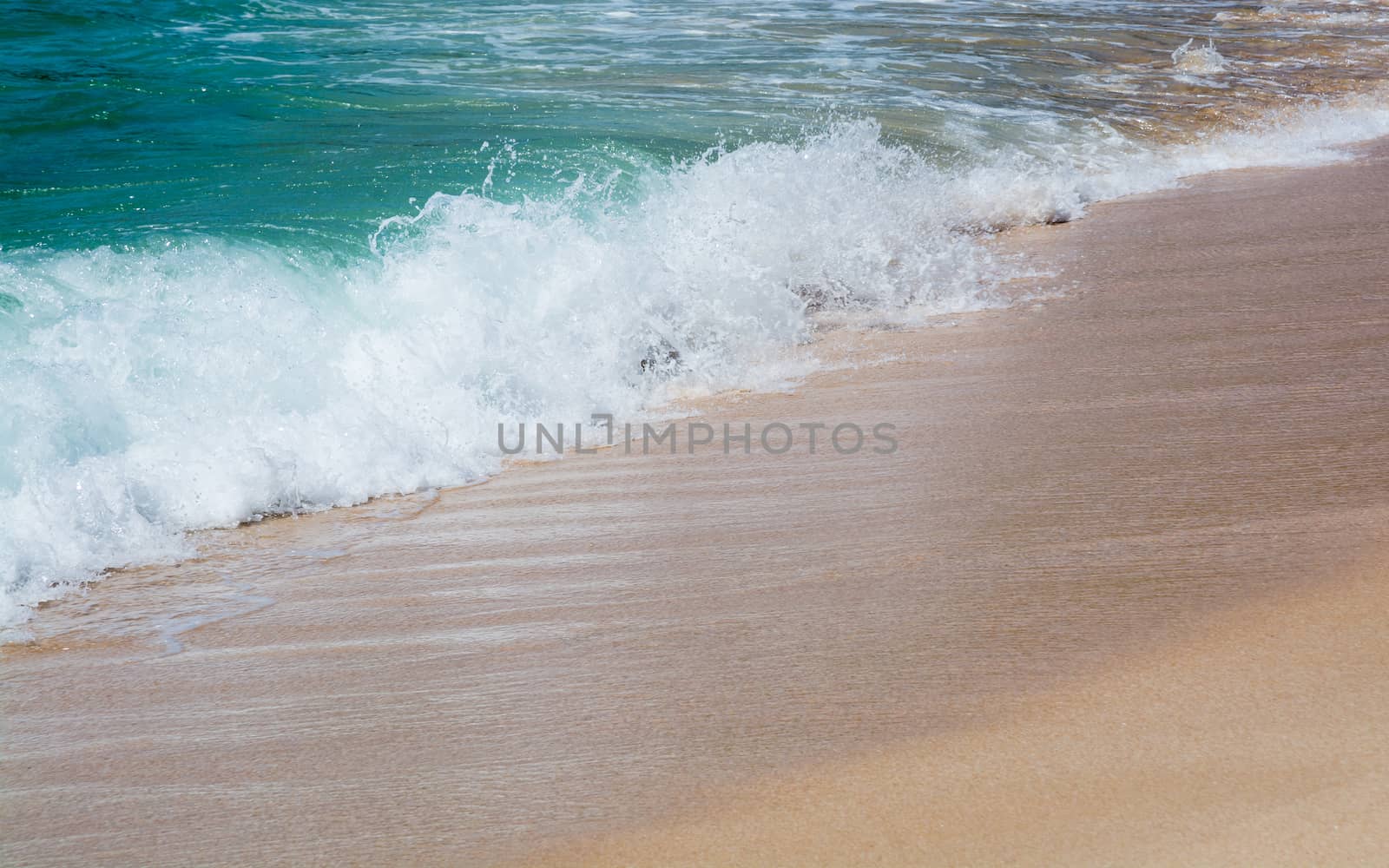 Green water and seaspray on sandy beach closeup in Southern Province, Sri Lanka, Asia.