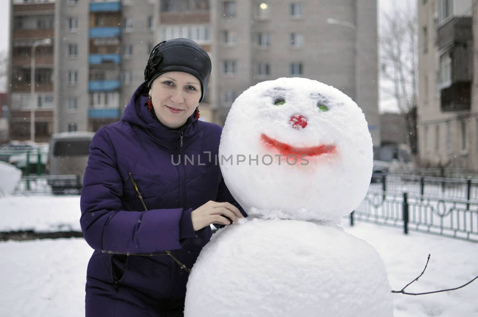 The woman near a snowman in the yard of the house. by veronka72