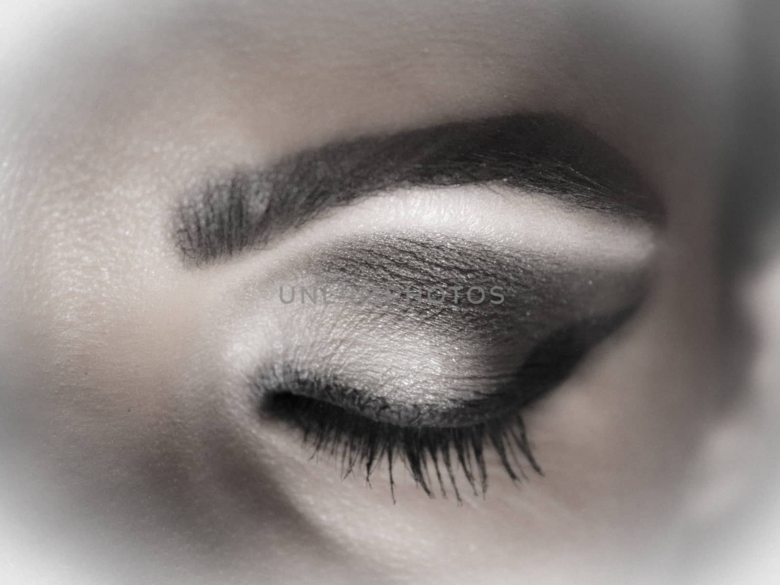 Closed eye makeup with shades of gray and black line.