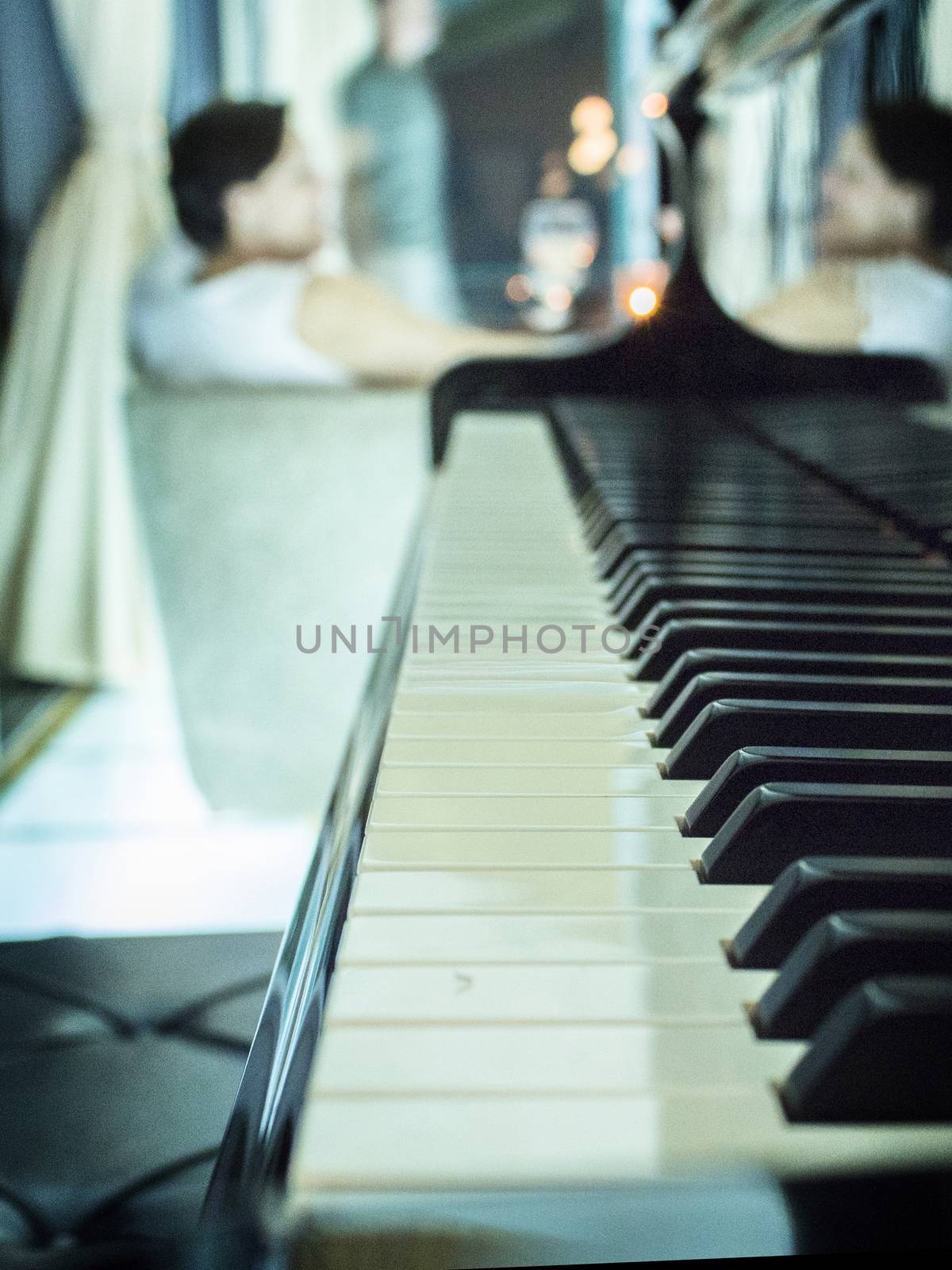 Black piano with blurred woman reflected in the piano.