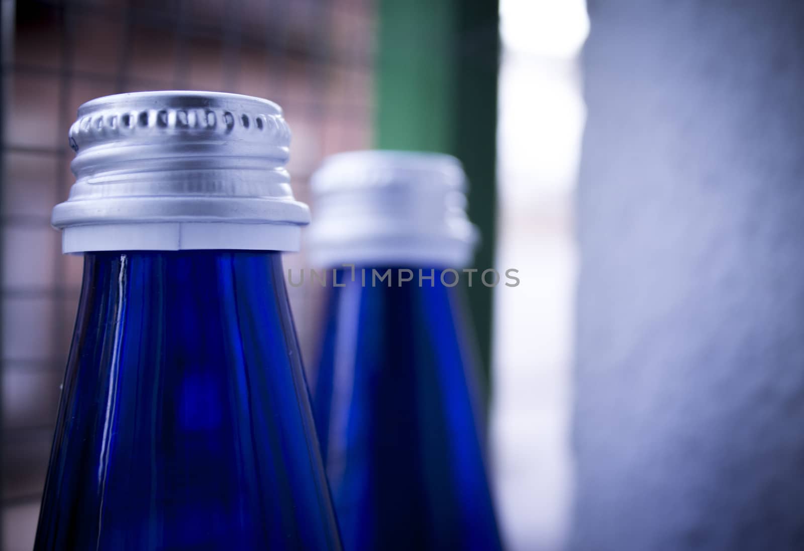 Blue Glass Bottles with gray stoppers on bottom half clear and half dark background.