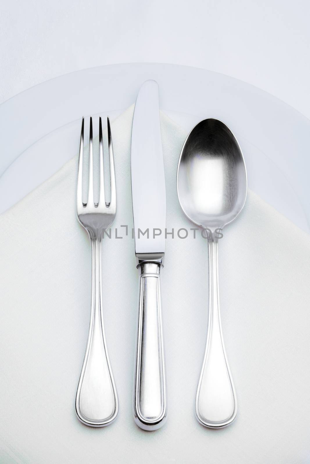 elegant silverware setting on plate with white cloth