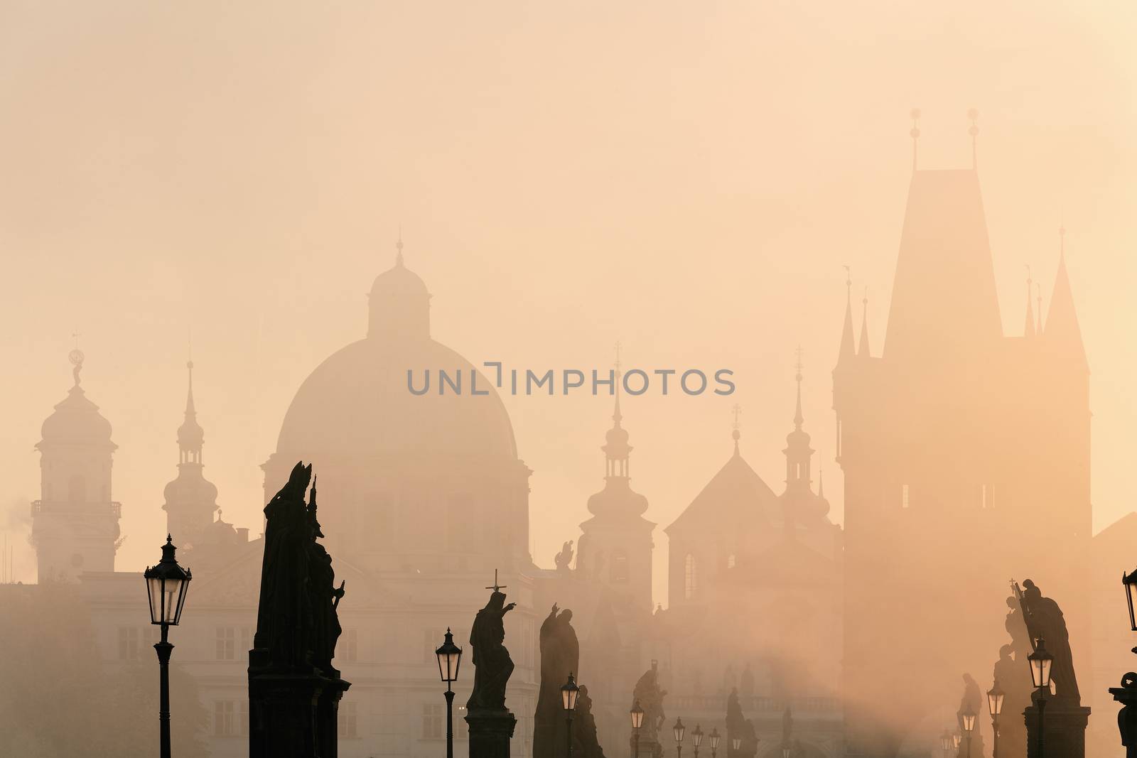 prague - charles bridge and towers of the old town on foggy morning