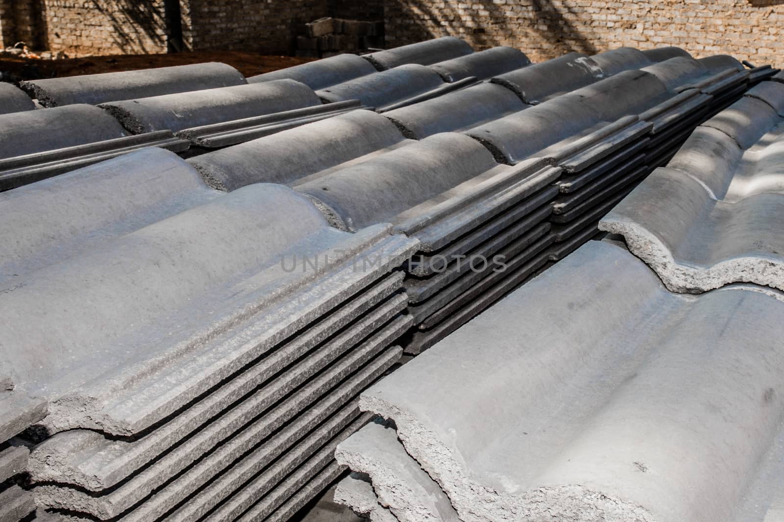 Roof tiles lying stacked ontop of each other as they were delivered at the incomplete house which they are inteded for.