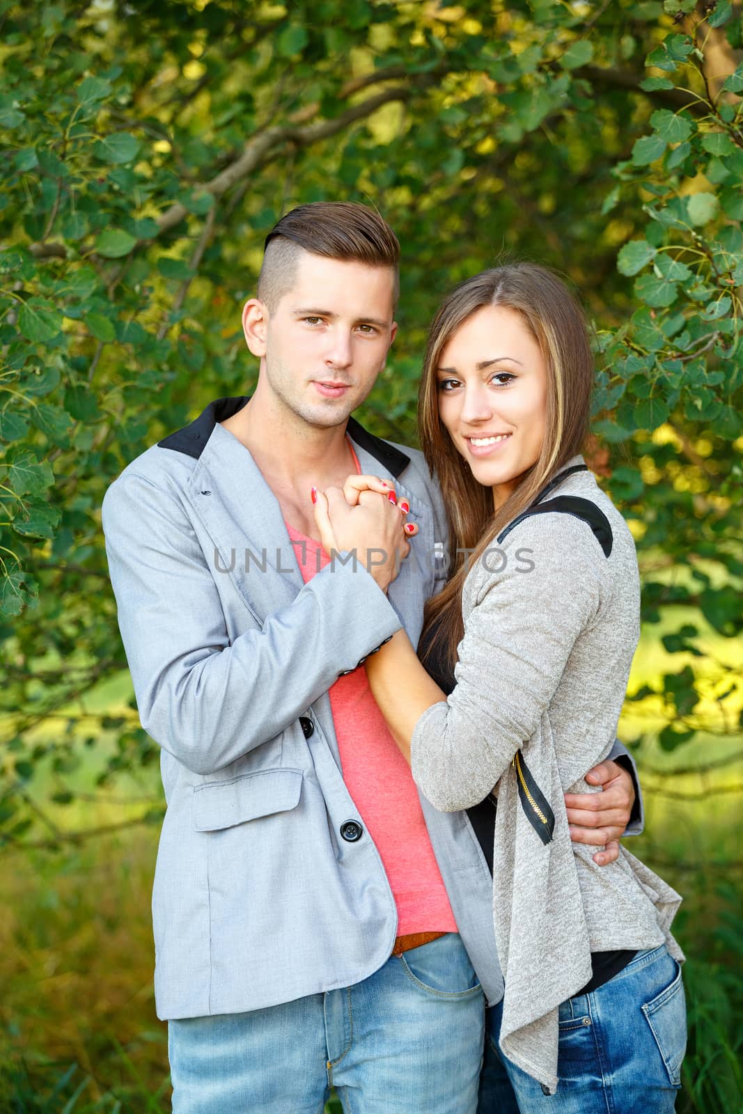 portrait of happy smiling young couple in love embracing outdoor at sunny day