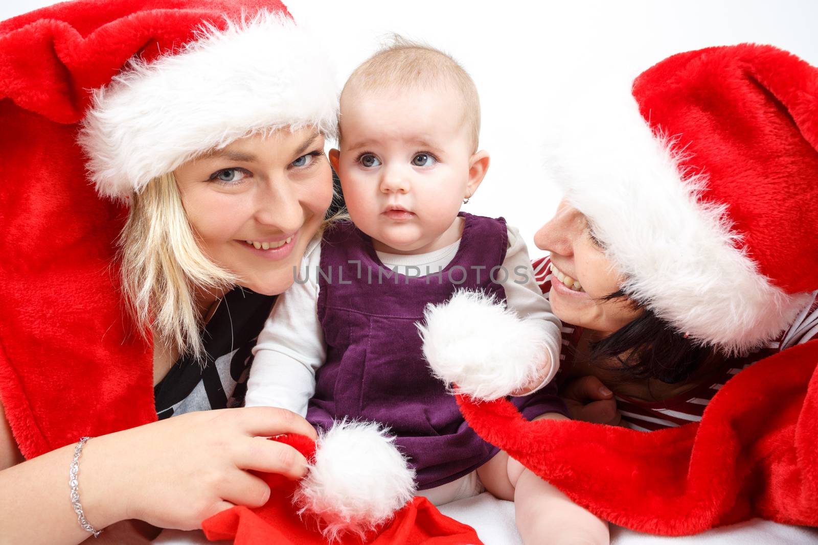 smiling infant baby with mother and her aunt with santa hats
