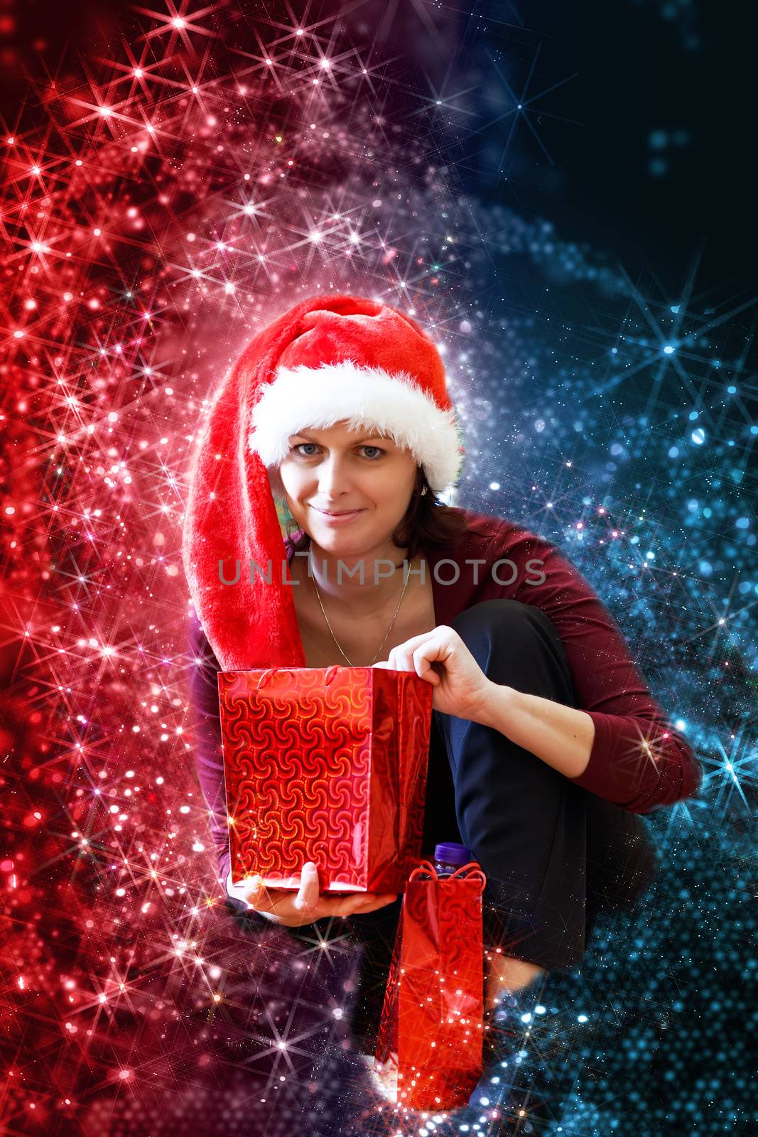 Beautiful middle age woman in red party santa hat sitting with gifts, with abstract background
