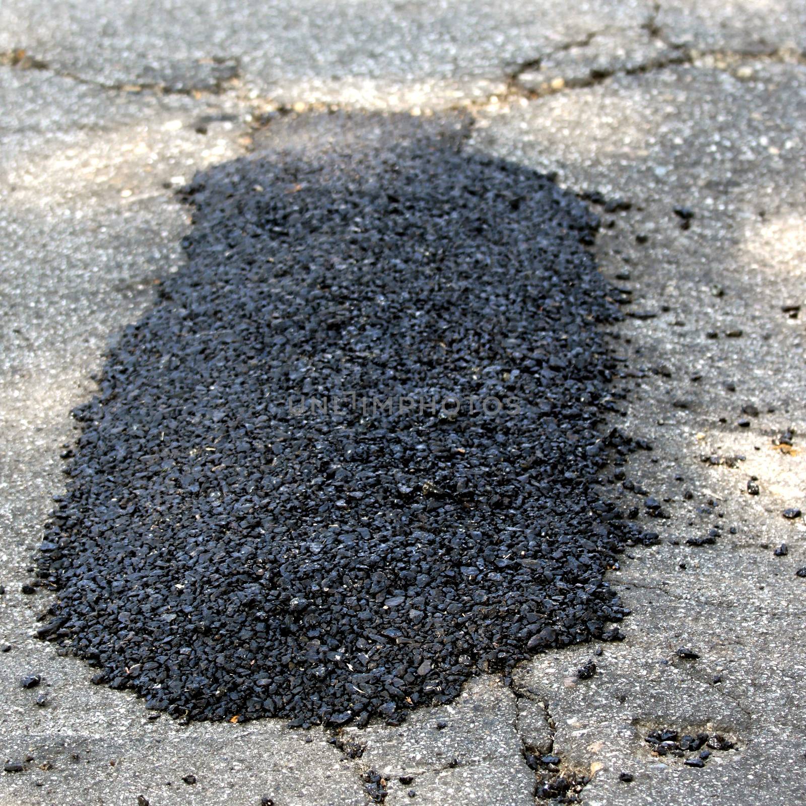 Repaired pothole with a black tarmac.