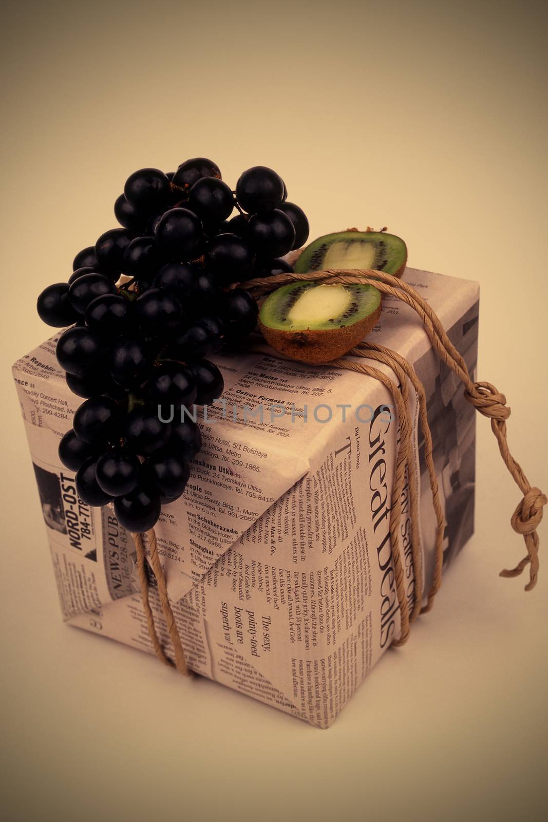 gift, stylishly packaged in an old newspaper box tied with twine with black grapes and kiwi, instagram image style