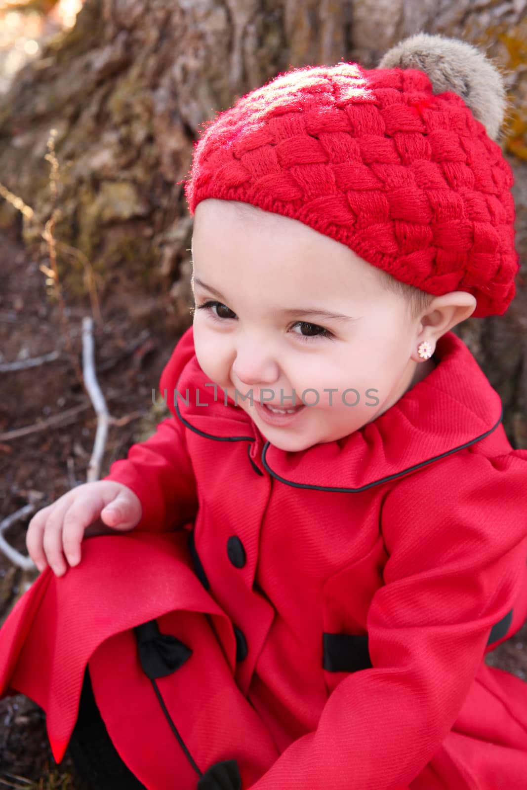 Little girl wearing a red coat and hat in the forest