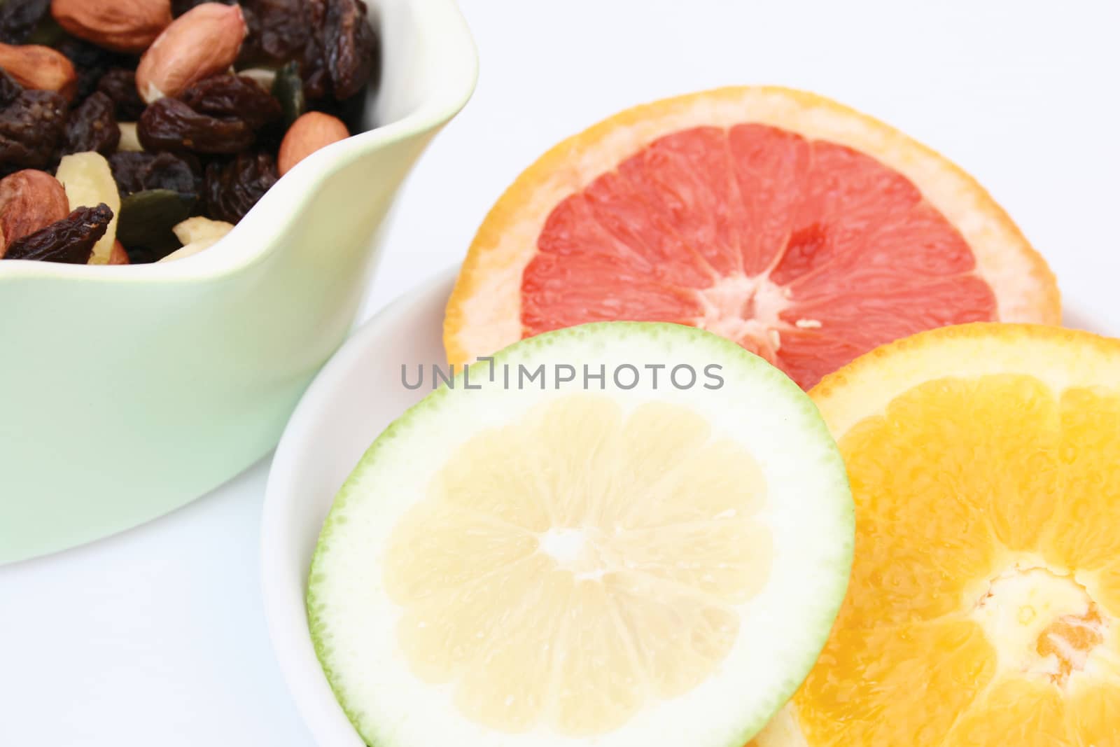 Bowl of mixed nuts and citrus on a white background