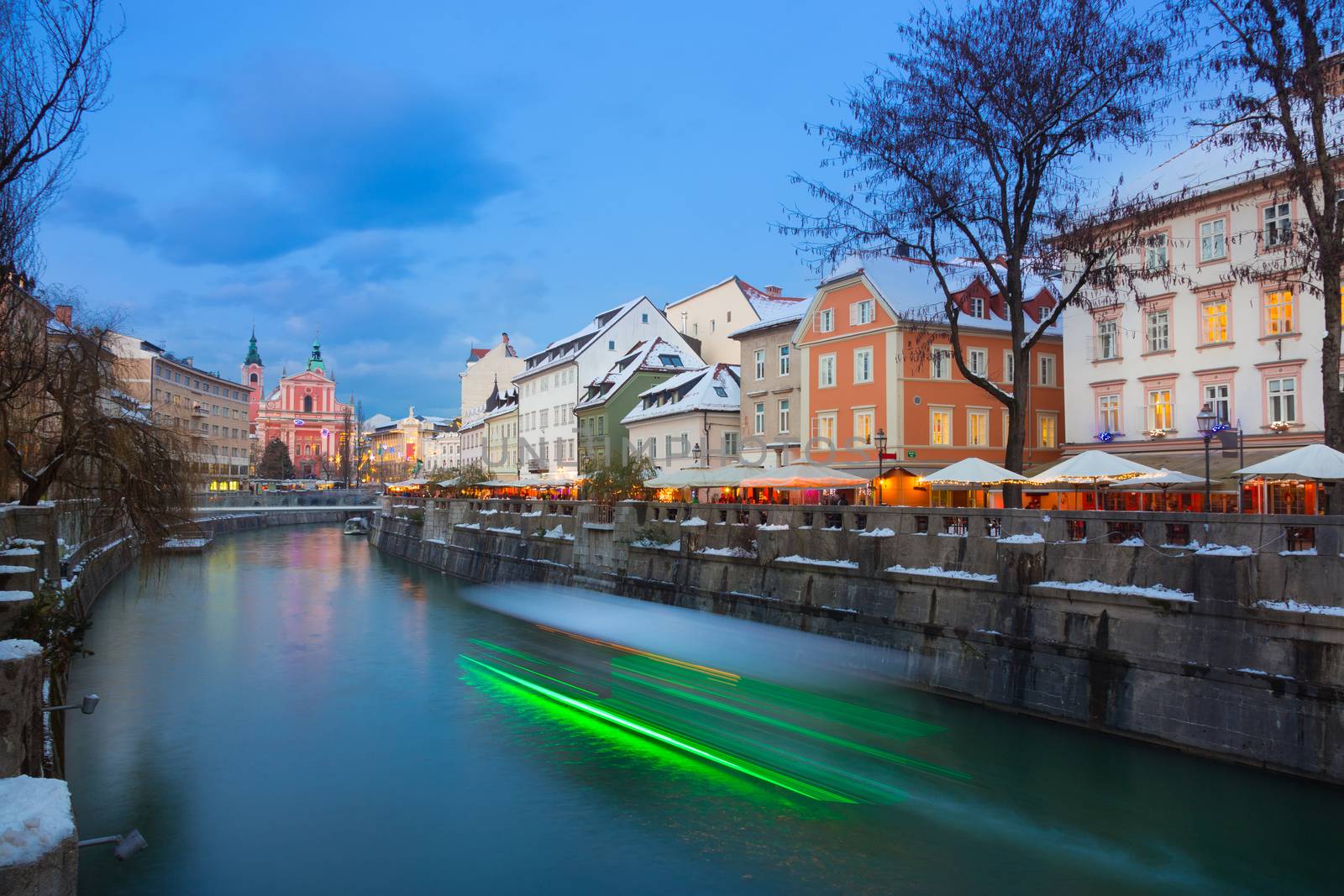 View of lively river Ljubljanica bank and Tromostovje in old city center decorated with Christmas lights at dusk. Ljubljana, Slovenia, Europe. 