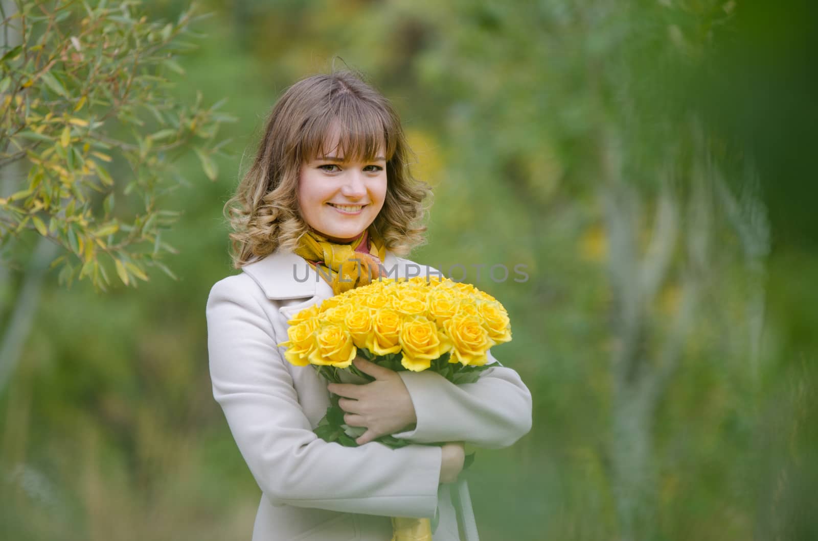 Young cute girl with a bouquet of yellow roses in autumn cool weather