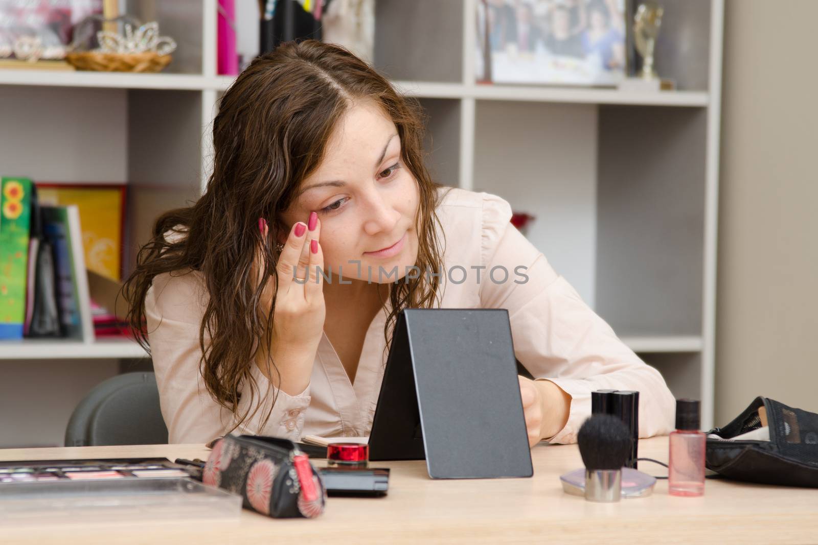 Young girl puts makeup in the office workplace