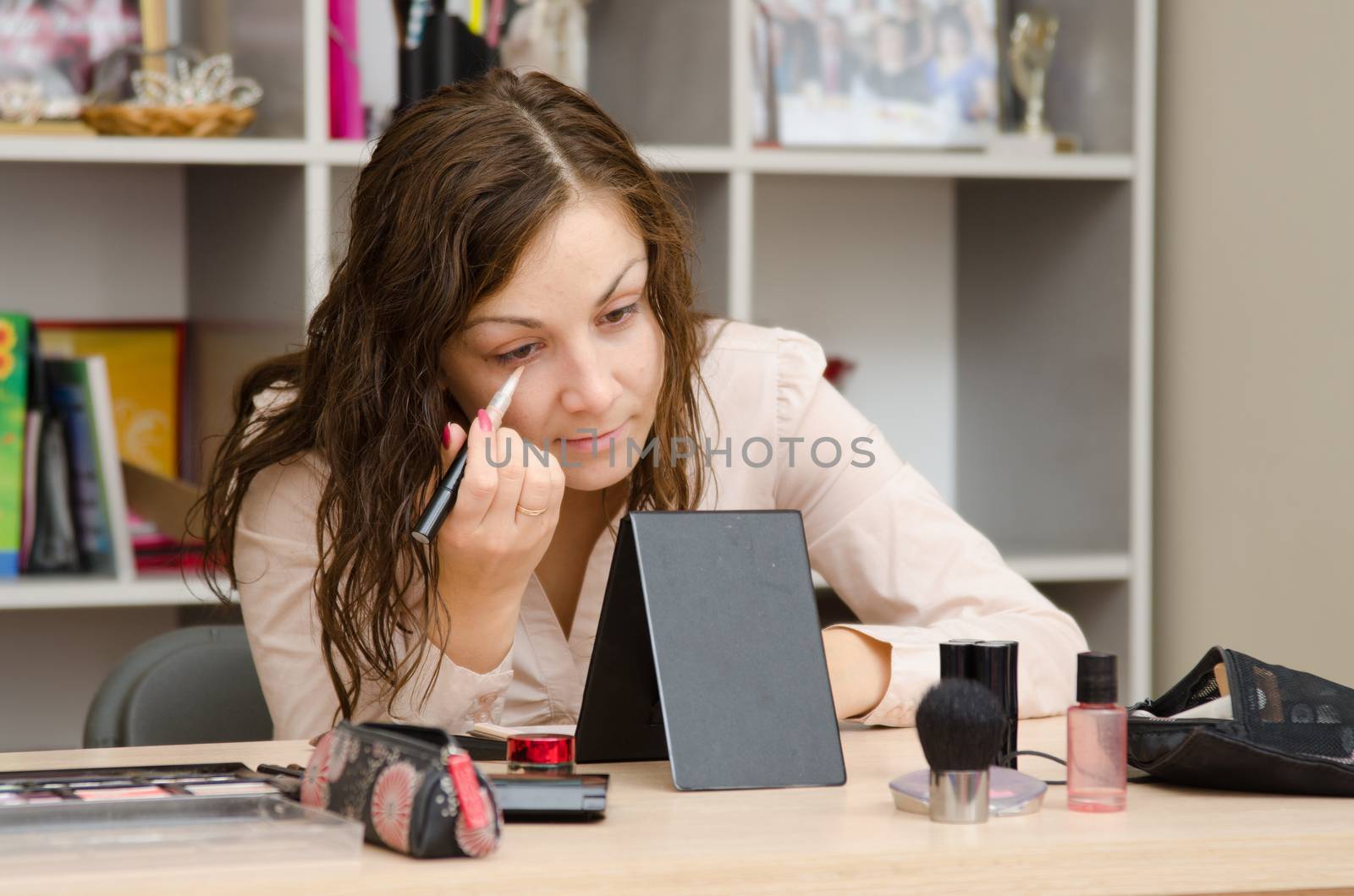 Young girl puts makeup in the office workplace