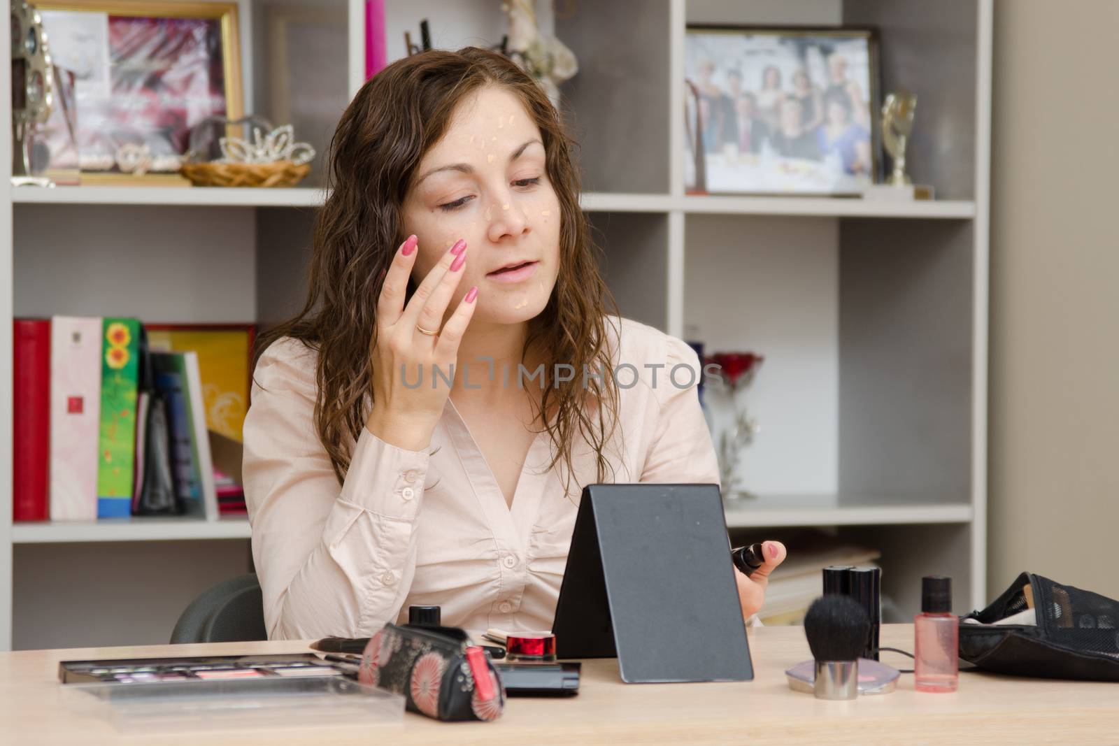 Young girl puts makeup in the office workplace