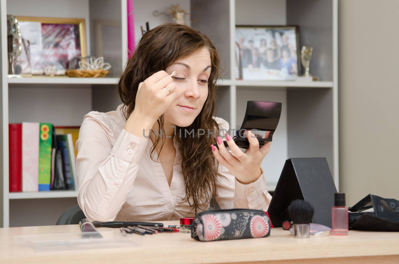 Young girl puts makeup in the office workplace