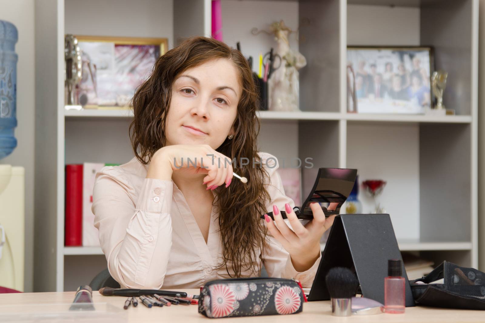 Young girl puts makeup in the office workplace