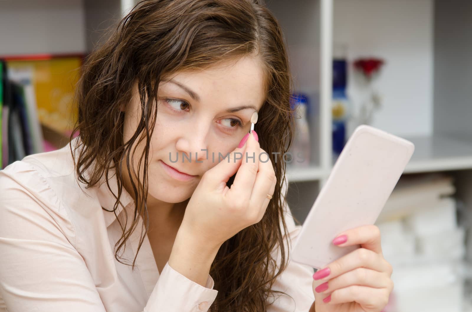 Young girl puts makeup in the office workplace